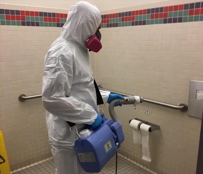 A SERVPRO tech wears PPE while cleaning a bathroom.