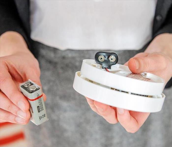 Woman installing 9 volt battery in smoke detector